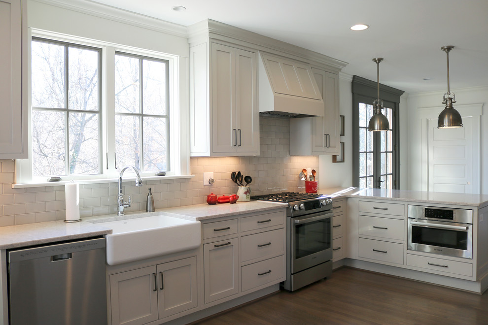 Inspiration for a large transitional galley medium tone wood floor and brown floor enclosed kitchen remodel with a farmhouse sink, shaker cabinets, gray cabinets, quartzite countertops, stainless steel appliances, beige backsplash, subway tile backsplash and a peninsula