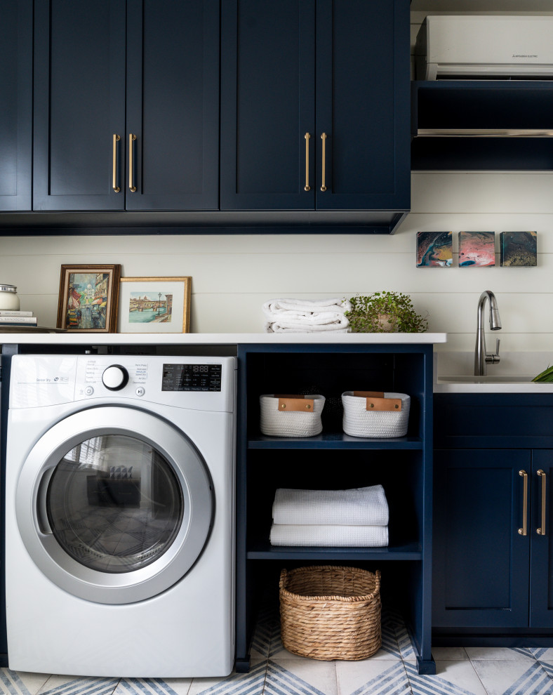 Large transitional galley dedicated laundry room in Nashville with an undermount sink, shaker cabinets, blue cabinets, quartz benchtops, shiplap splashback, white walls, porcelain floors, a side-by-side washer and dryer, multi-coloured floor, white benchtop and planked wall panelling.