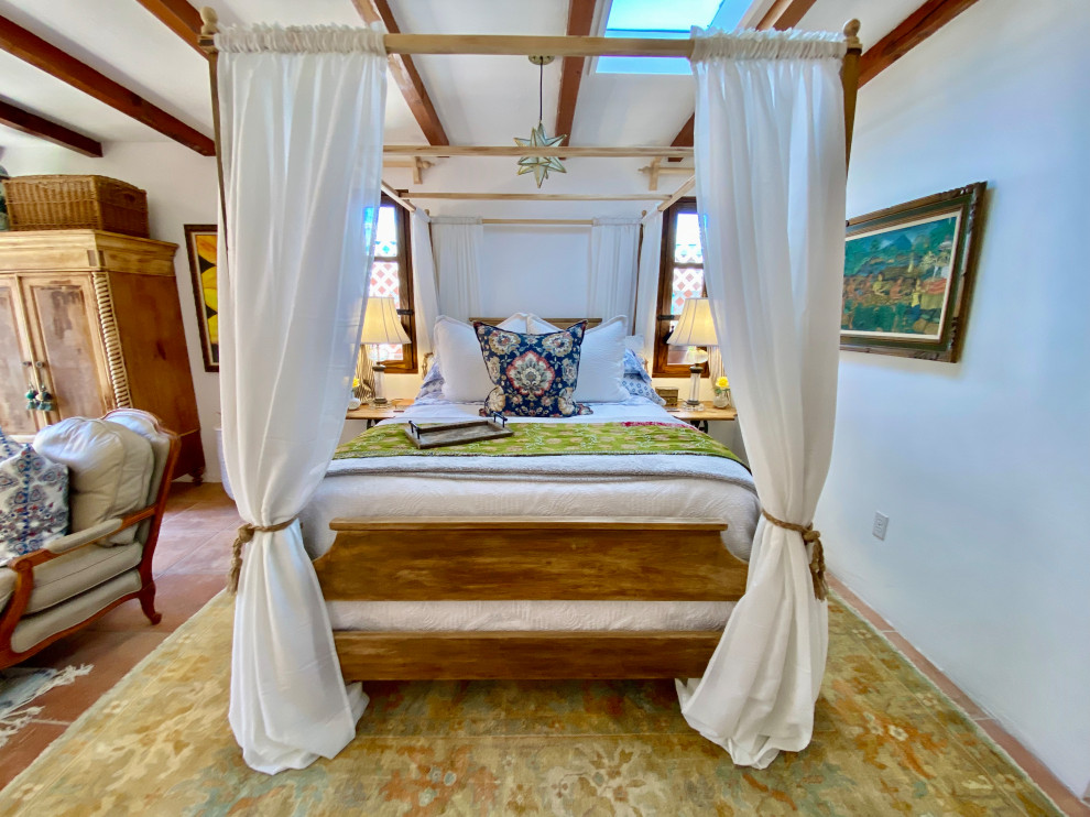Photo of a medium sized nautical guest bedroom in San Diego with white walls, porcelain flooring, a corner fireplace, a plastered fireplace surround, orange floors and exposed beams.
