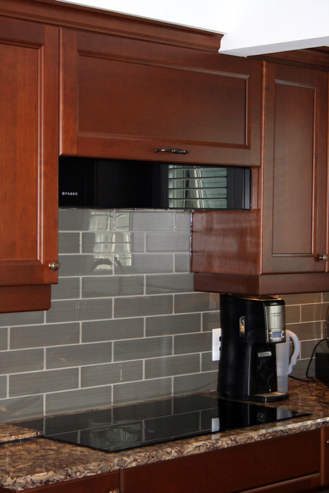 Mid-sized transitional l-shaped linoleum floor enclosed kitchen photo in Toronto with an undermount sink, shaker cabinets, medium tone wood cabinets, quartz countertops, gray backsplash, ceramic backsplash, black appliances and an island