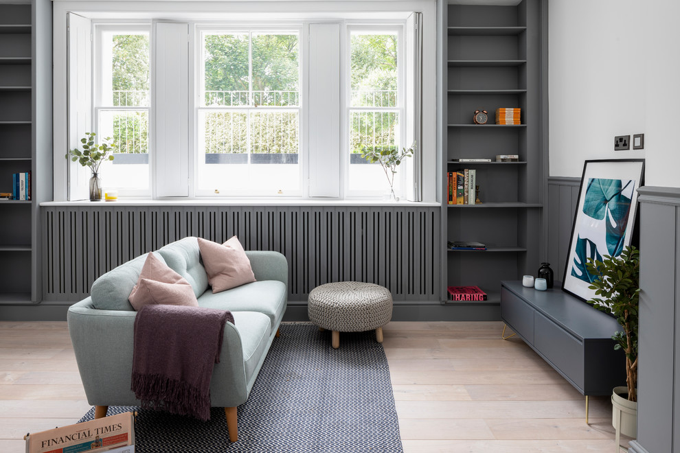 Scandinavian family room in London with a library, multi-coloured walls, light hardwood floors, no fireplace and beige floor.