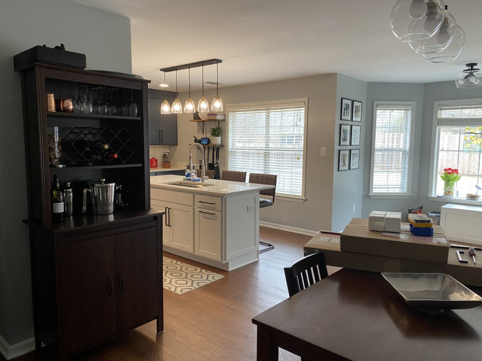 Mid-sized transitional u-shaped brown floor enclosed kitchen photo with an undermount sink, shaker cabinets, blue cabinets, quartz countertops, white backsplash, stainless steel appliances, an island and white countertops