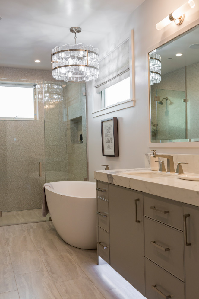 This is an example of a mid-sized beach style master bathroom in Los Angeles with beaded inset cabinets, grey cabinets, a freestanding tub, a curbless shower, a two-piece toilet, grey walls, porcelain floors, an undermount sink, engineered quartz benchtops, beige floor, a hinged shower door, white benchtops, a shower seat, a double vanity, a built-in vanity and wallpaper.