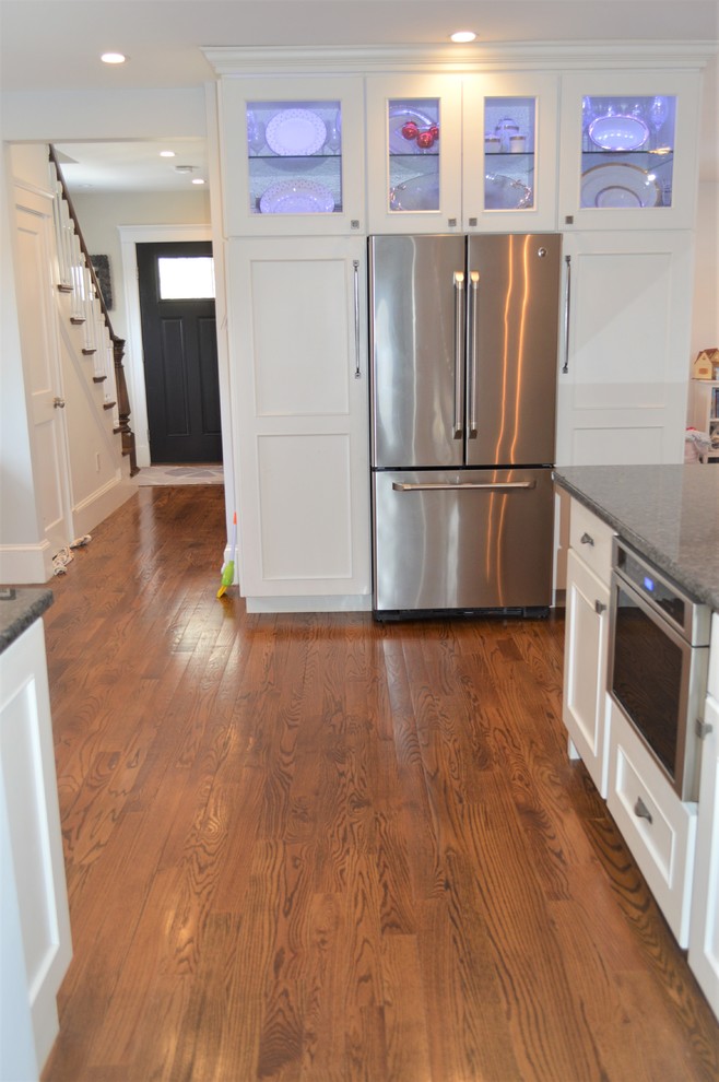Eat-in kitchen - mid-sized transitional l-shaped medium tone wood floor eat-in kitchen idea in Boston with an undermount sink, recessed-panel cabinets, white cabinets, granite countertops, gray backsplash, cement tile backsplash, stainless steel appliances, a peninsula and blue countertops