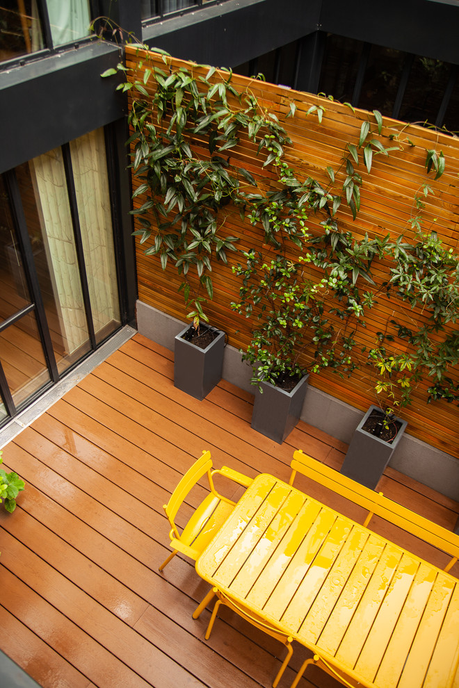 This is an example of a small transitional backyard patio in Paris with a container garden and decking.