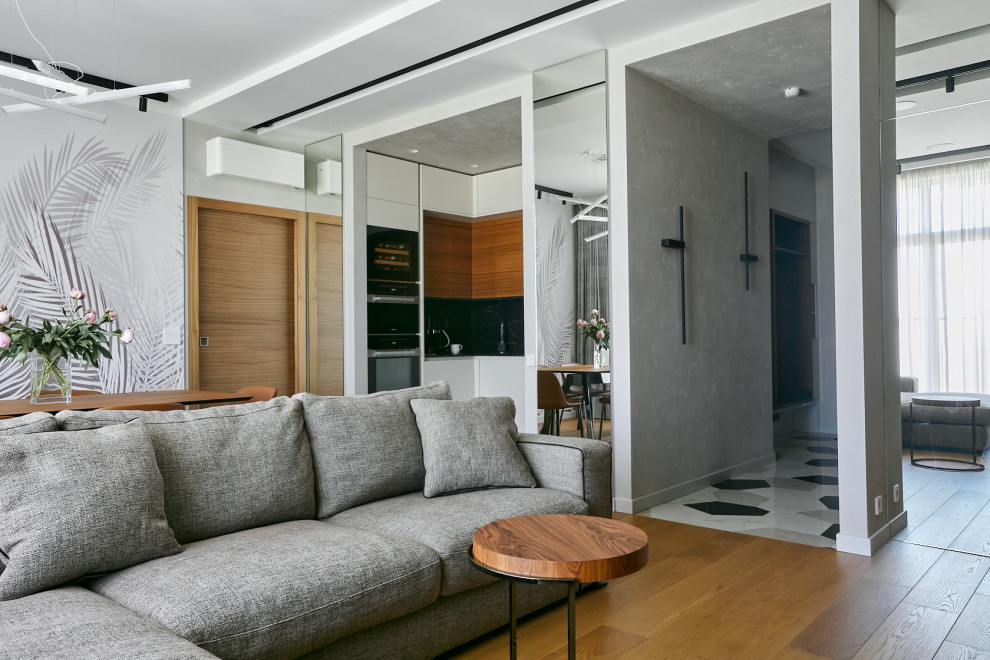 Пример оригинального дизайна: открытая гостиная комната в современном стиле с серыми стенами, паркетным полом среднего тона и многоуровневым потолком