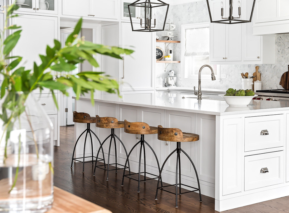 Inspiration for a large transitional eat-in kitchen in Chicago with a farmhouse sink, beaded inset cabinets, white cabinets, quartz benchtops, grey splashback, marble splashback, stainless steel appliances, medium hardwood floors, with island and brown floor.