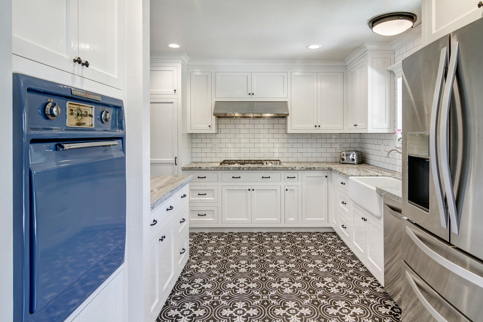 Photo of a small country galley kitchen pantry in San Diego with a farmhouse sink, shaker cabinets, white cabinets, granite benchtops, white splashback, porcelain splashback, stainless steel appliances, ceramic floors and a peninsula.
