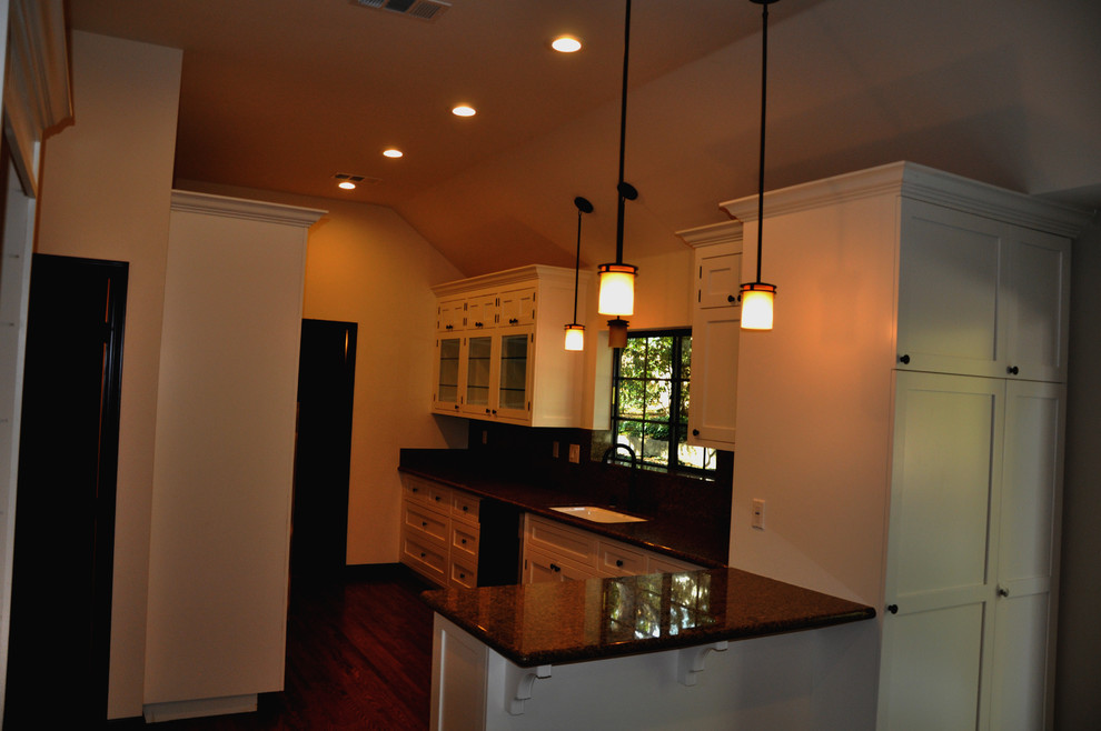 Photo of a mid-sized traditional l-shaped separate kitchen in Los Angeles with flat-panel cabinets, white cabinets, granite benchtops, stone slab splashback, dark hardwood floors, a peninsula and a single-bowl sink.