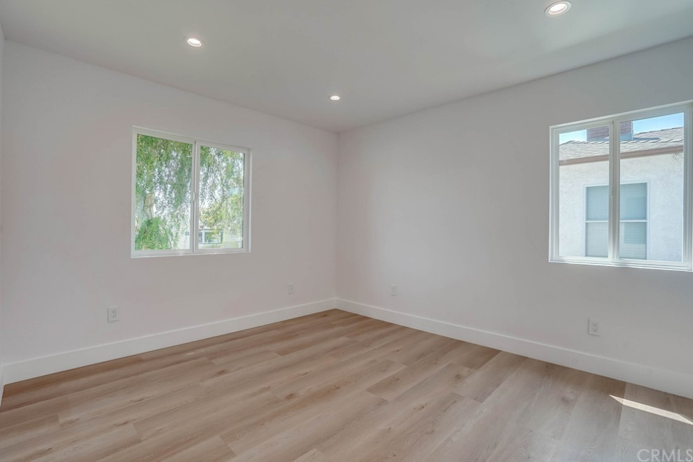 Immagine di una camera da letto design con pareti bianche, parquet chiaro e pavimento marrone