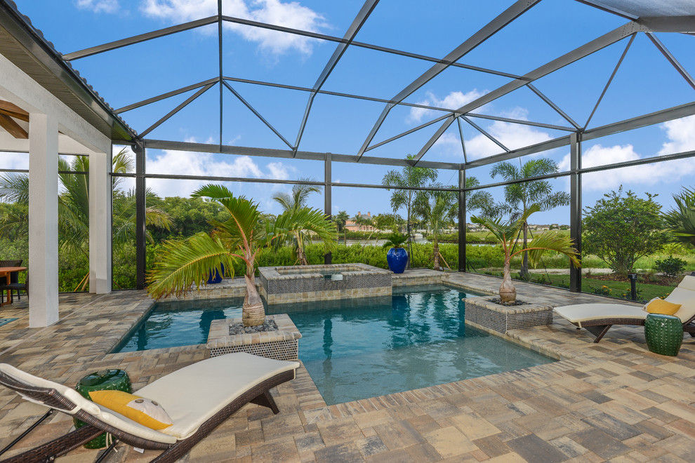 Photo of a large contemporary indoor custom-shaped pool in Tampa with concrete pavers.
