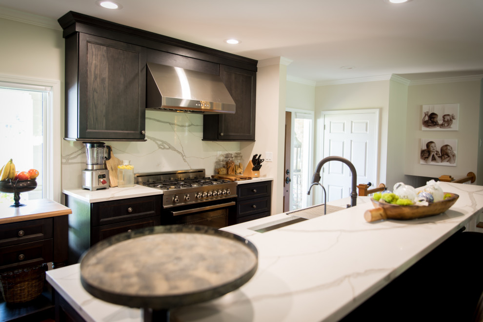Large mountain style l-shaped light wood floor and brown floor eat-in kitchen photo with an undermount sink, recessed-panel cabinets, dark wood cabinets, quartz countertops, white backsplash, stainless steel appliances, an island, white countertops and quartz backsplash