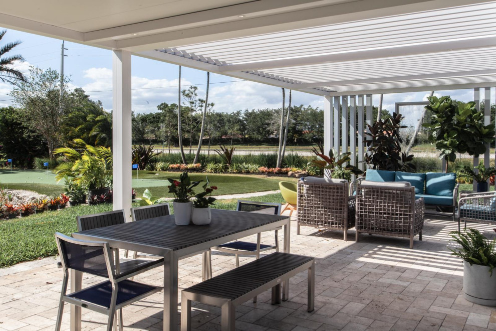 Example of a large trendy backyard stone patio design in Miami with a pergola