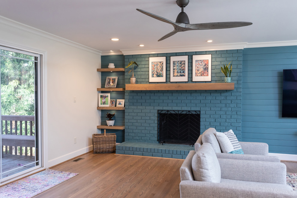 Großes, Offenes Klassisches Wohnzimmer mit blauer Wandfarbe, braunem Holzboden, Kamin, Kaminumrandung aus Backstein, TV-Wand, braunem Boden und Holzdielenwänden in Raleigh
