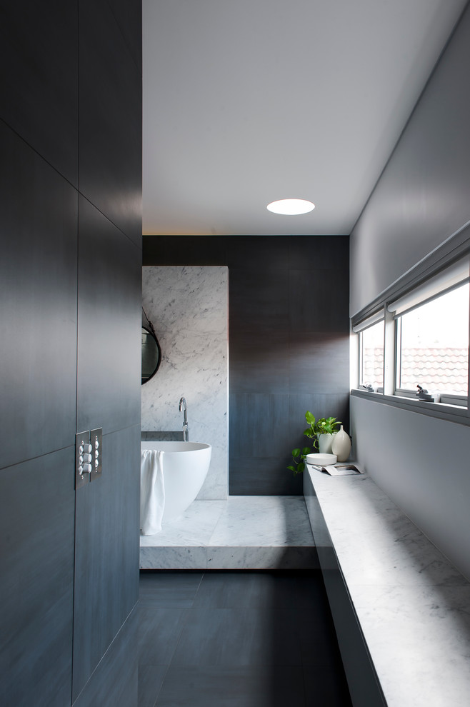 Photo of a large contemporary master bathroom in Sydney with an integrated sink, furniture-like cabinets, white cabinets, solid surface benchtops, a freestanding tub, an open shower, a one-piece toilet, gray tile, ceramic tile, grey walls and ceramic floors.