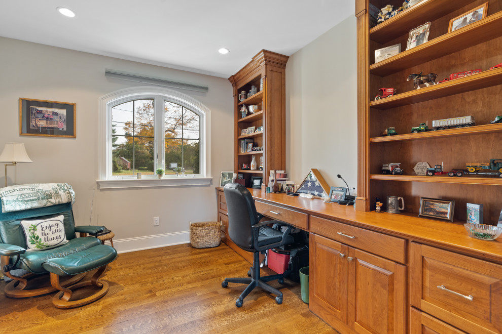 Inspiration for a large country study room in Bridgeport with grey walls, medium hardwood floors, no fireplace, a built-in desk and brown floor.