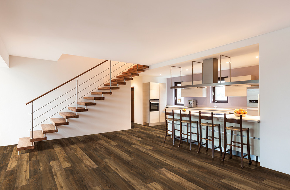 Transitional u-shaped light wood floor and beige floor enclosed kitchen photo in Orlando with an undermount sink, flat-panel cabinets, dark wood cabinets, granite countertops, white backsplash, subway tile backsplash, stainless steel appliances and an island