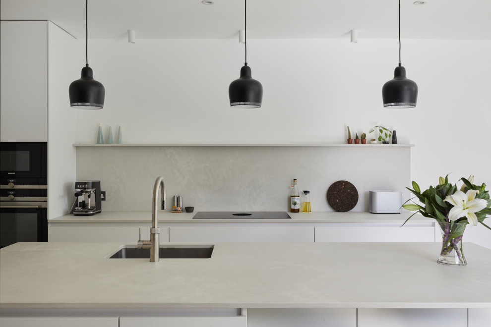 Inspiration for a mid-sized modern l-shaped open plan kitchen in London with flat-panel cabinets, white cabinets, quartz benchtops, grey splashback, with island and grey benchtop.
