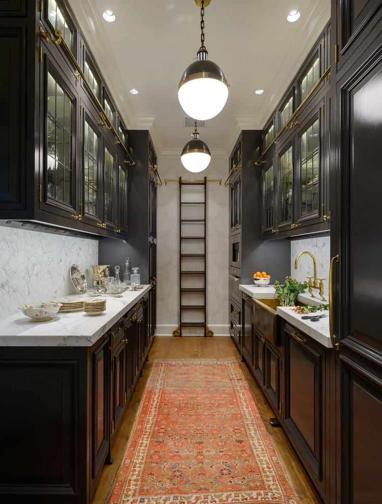 Inspiration for a mid-sized traditional galley separate kitchen in Seattle with a farmhouse sink, raised-panel cabinets, black cabinets, marble benchtops, white splashback, medium hardwood floors, no island and marble splashback.