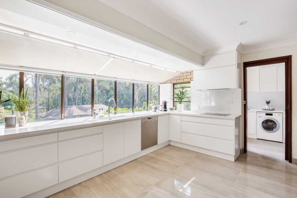 This is an example of a large contemporary galley eat-in kitchen in Newcastle - Maitland with an undermount sink, flat-panel cabinets, white cabinets, stainless steel appliances, white benchtop, quartz benchtops, window splashback, light hardwood floors and exposed beam.