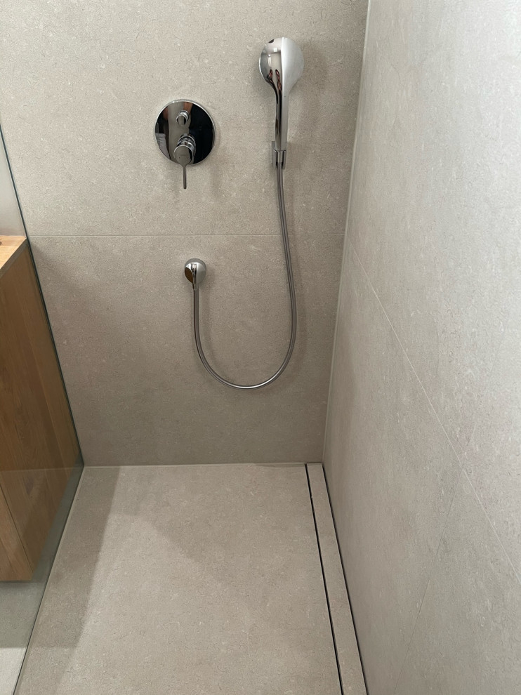 Idéer för att renovera ett mellanstort funkis brun brunt badrum med dusch, med luckor med lamellpanel, bruna skåp, en kantlös dusch, grå kakel, grå väggar, betonggolv, ett fristående handfat, träbänkskiva, grått golv och med dusch som är öppen