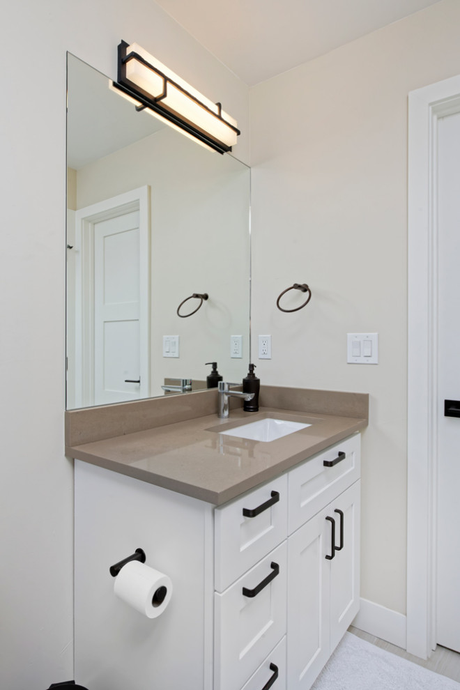 Example of a mid-sized trendy powder room design in Other with shaker cabinets, black cabinets, a one-piece toilet, orange walls, a drop-in sink, granite countertops, white countertops and a built-in vanity