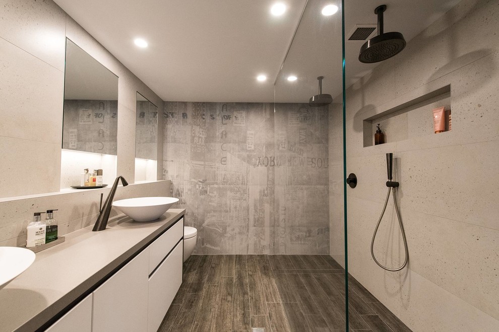 Inspiration for a large industrial master bathroom in Sydney with flat-panel cabinets, white cabinets, an open shower, stone slab, a vessel sink, an open shower, a one-piece toilet, porcelain floors, beige tile, beige walls, engineered quartz benchtops, brown floor, beige benchtops, a niche and a double vanity.