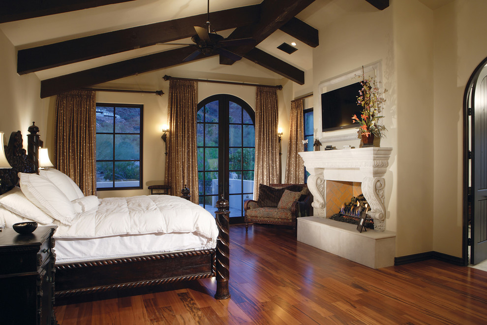 Large traditional master bedroom in Phoenix with beige walls, medium hardwood floors, a standard fireplace and a stone fireplace surround.