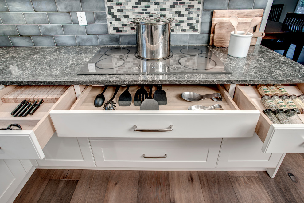 Eat-in kitchen - mid-sized transitional l-shaped medium tone wood floor and brown floor eat-in kitchen idea in Seattle with a double-bowl sink, shaker cabinets, white cabinets, quartz countertops, gray backsplash, ceramic backsplash, stainless steel appliances, two islands and gray countertops