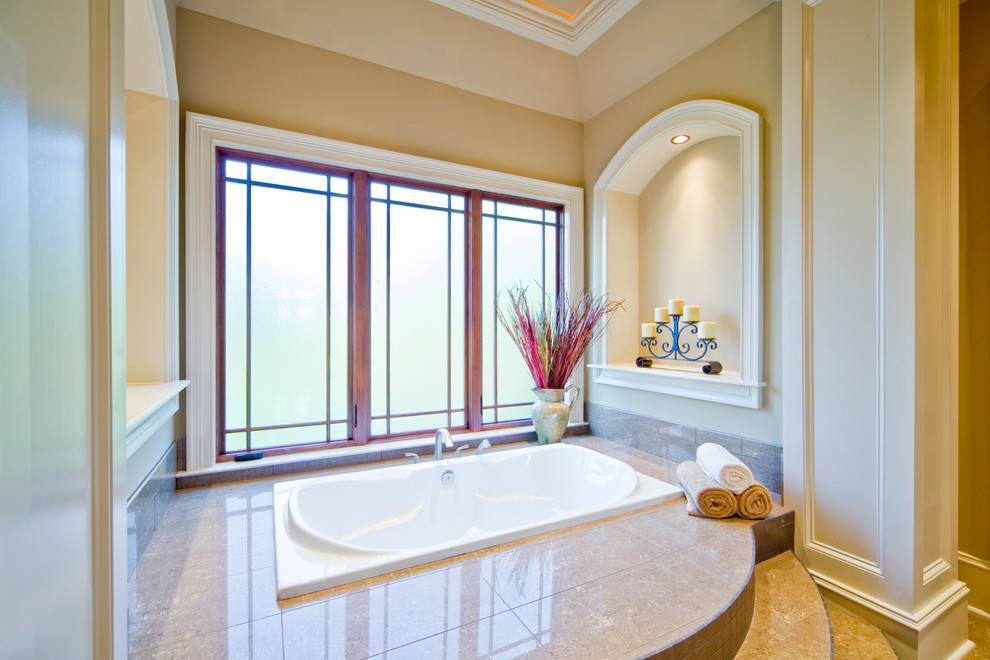 This is an example of an arts and crafts master bathroom in Atlanta with a drop-in tub, beige walls and beige floor.