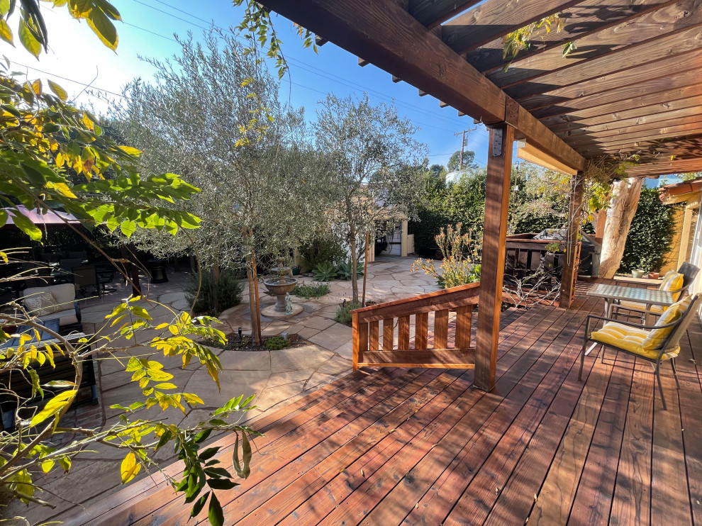This is an example of a mid-sized mediterranean backyard full sun xeriscape for spring in Los Angeles with a fire feature, brick pavers and a wood fence.