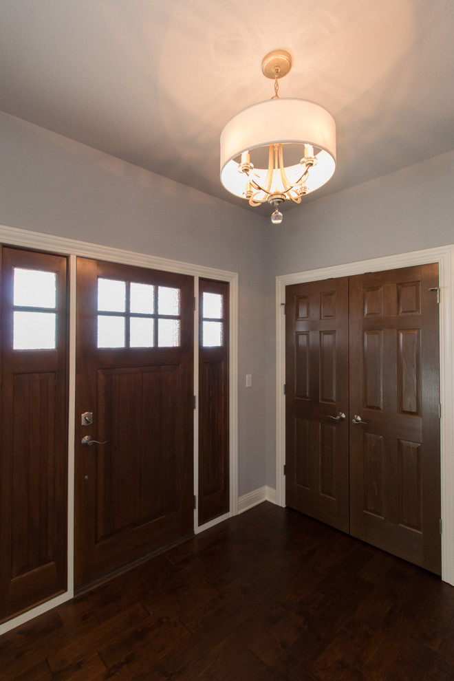 Foyer - mid-sized modern medium tone wood floor foyer idea in Milwaukee with gray walls and a dark wood front door