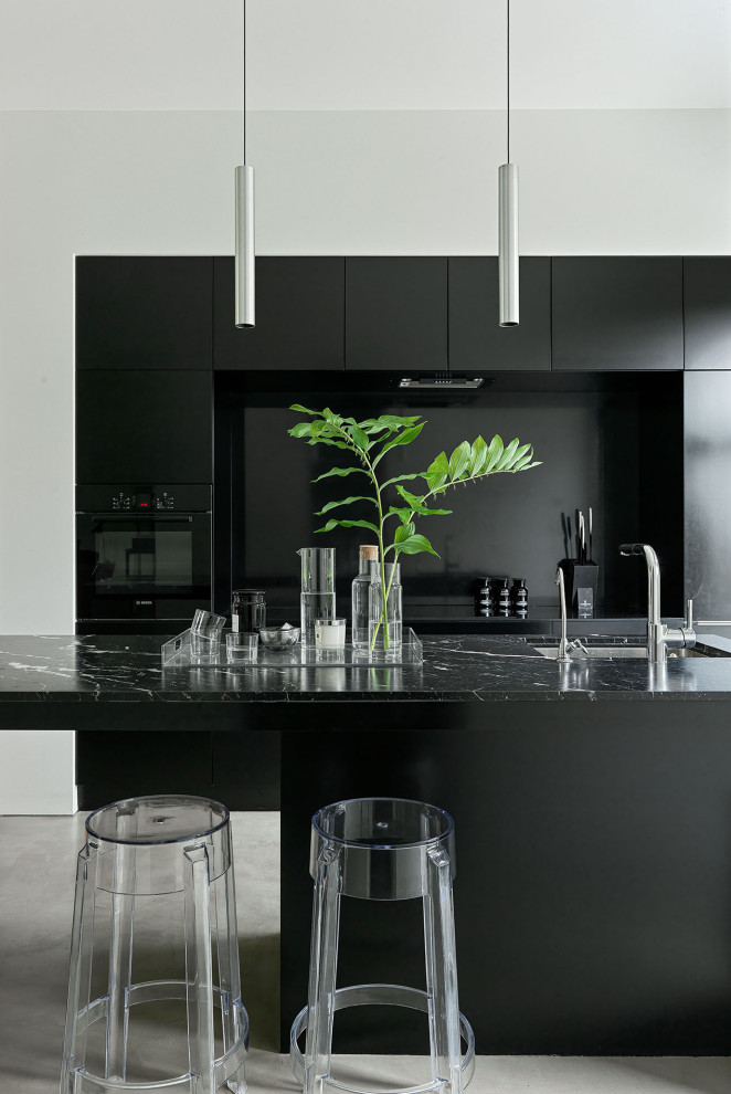 Large contemporary galley kitchen in Moscow with an undermount sink, flat-panel cabinets, black cabinets, black splashback, black appliances, with island, grey floor and black benchtop.