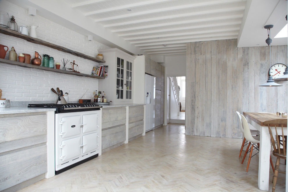 This is an example of a scandinavian single-wall eat-in kitchen in London with flat-panel cabinets, light wood cabinets and white appliances.