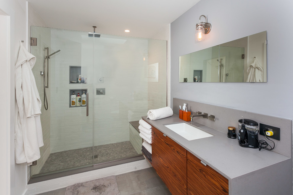 Design ideas for a mid-sized transitional master bathroom in Los Angeles with flat-panel cabinets, medium wood cabinets, an alcove shower, a two-piece toilet, white tile, porcelain tile, white walls, concrete floors, an undermount sink, quartzite benchtops, grey benchtops, grey floor and a hinged shower door.