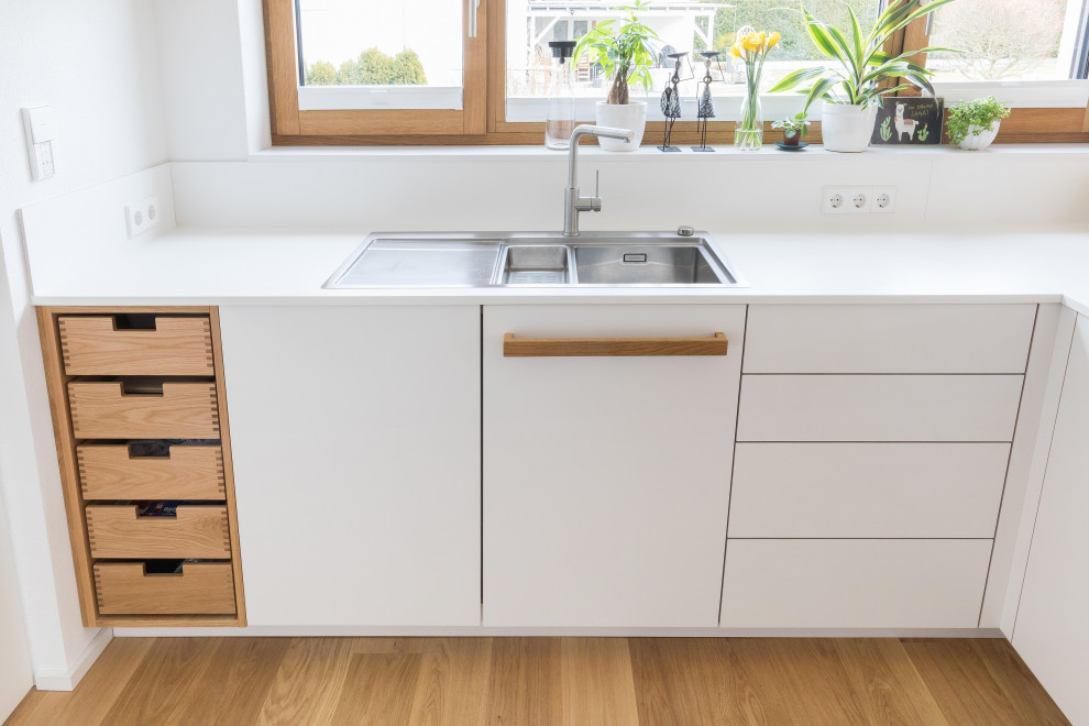 Inspiration for a large scandinavian l-shaped open plan kitchen in Stuttgart with white cabinets, white splashback and recessed.