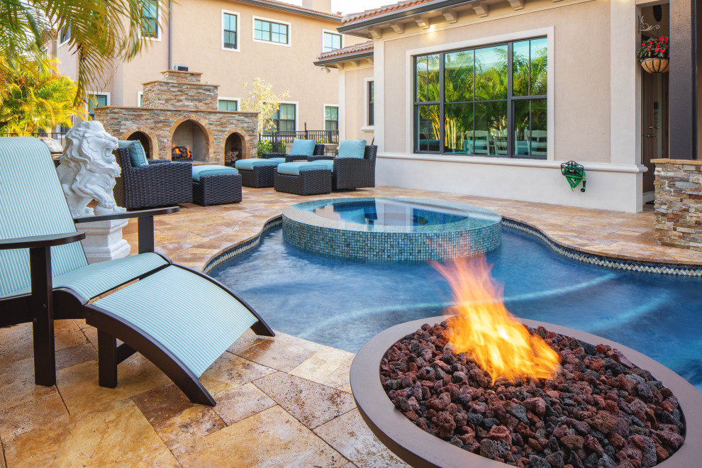 Mid-sized backyard custom-shaped pool in Miami with a water feature and natural stone pavers.