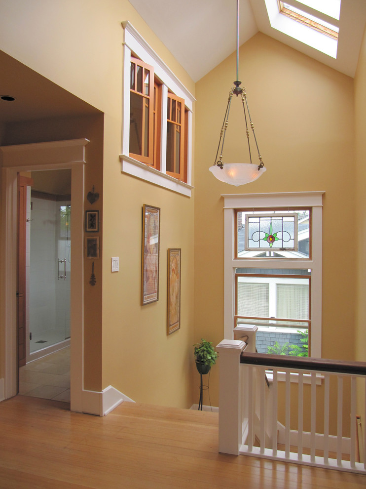 This is an example of an expansive eclectic hallway in Seattle with yellow walls and light hardwood floors.