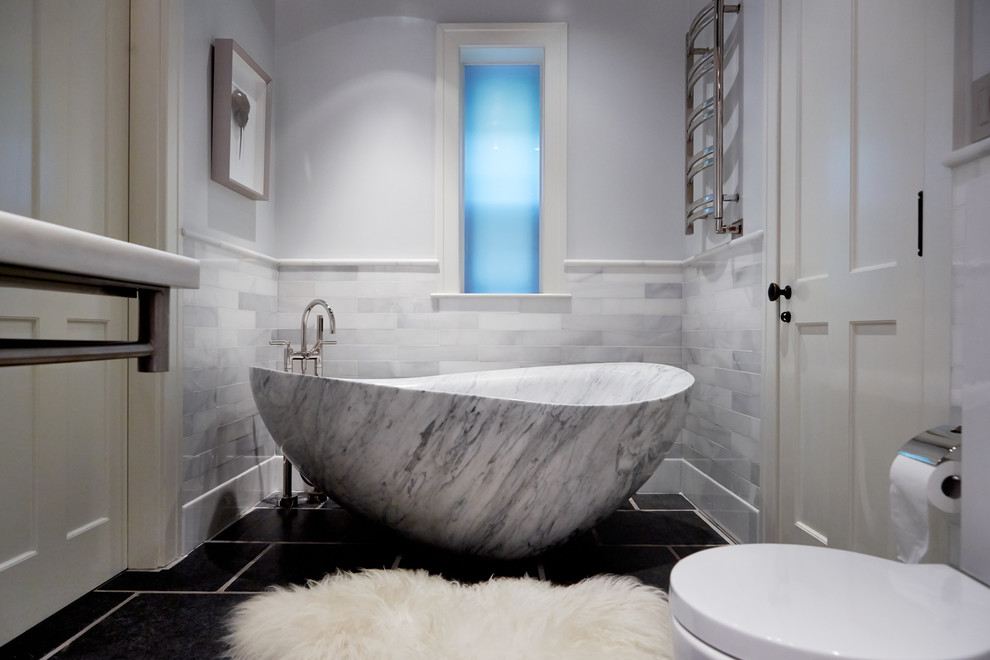 Mid-sized transitional master bathroom in Boston with a freestanding tub, gray tile, marble, grey walls, ceramic floors and black floor.