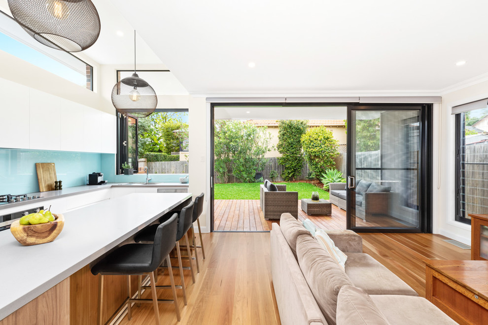 Inspiration for a large contemporary open concept living room in Sydney with white walls, medium hardwood floors, a wall-mounted tv and brown floor.