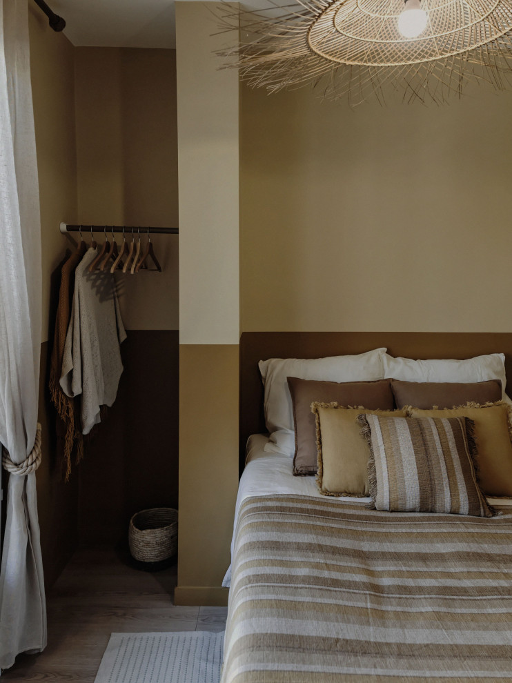 Esempio di una camera da letto mediterranea di medie dimensioni con pareti gialle, pavimento in legno massello medio, nessun camino e pavimento marrone
