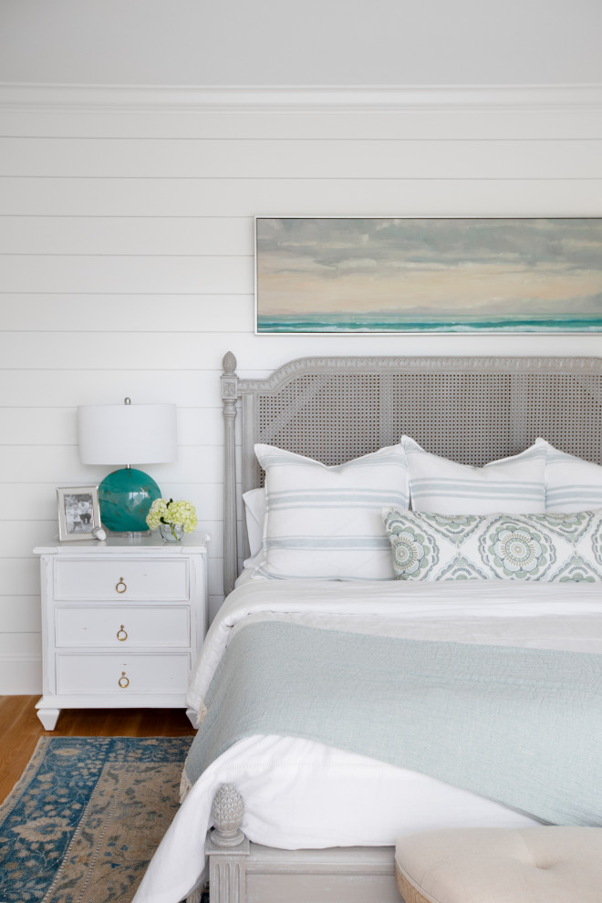 Beach style master bedroom in Charleston with white walls, light hardwood floors and planked wall panelling.