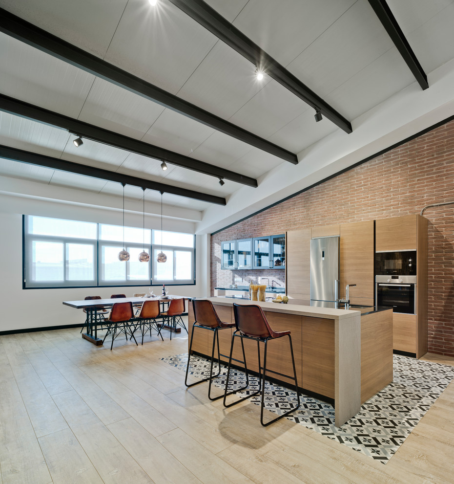 This is an example of a large contemporary single-wall eat-in kitchen in Madrid with flat-panel cabinets, medium wood cabinets, light hardwood floors, with island, stainless steel appliances and beige floor.
