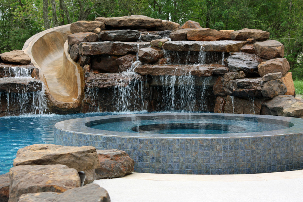 Design ideas for a large traditional backyard custom-shaped natural pool in Houston with a water slide and natural stone pavers.