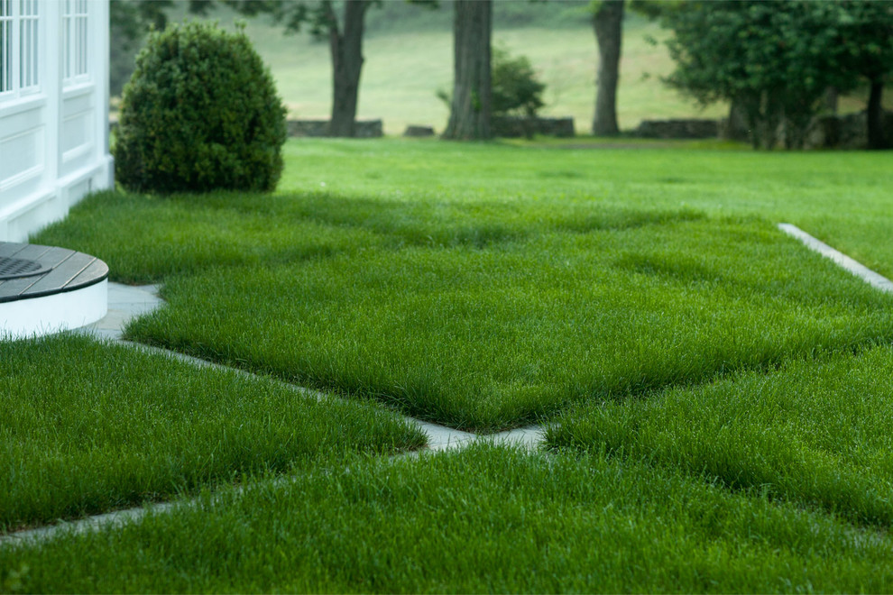 This is an example of a mid-sized transitional full sun backyard stone formal garden in New York for summer.
