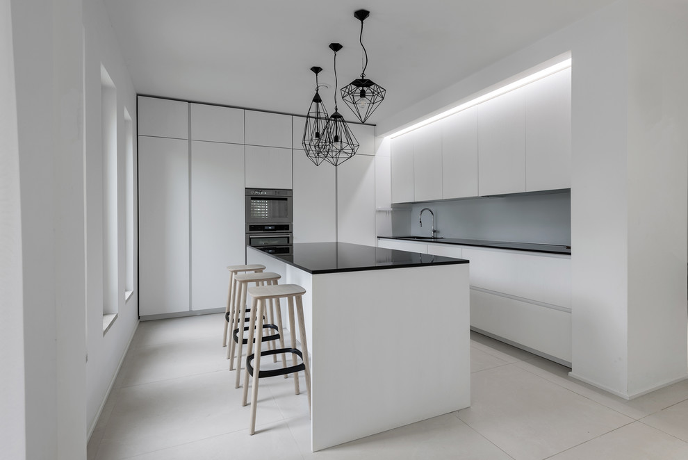 Design ideas for a modern l-shaped kitchen in Other with flat-panel cabinets, white cabinets, grey splashback, with island and white floor.