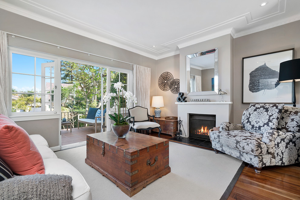 Photo of a large traditional enclosed living room in Sydney with grey walls, medium hardwood floors, a standard fireplace, a plaster fireplace surround and no tv.