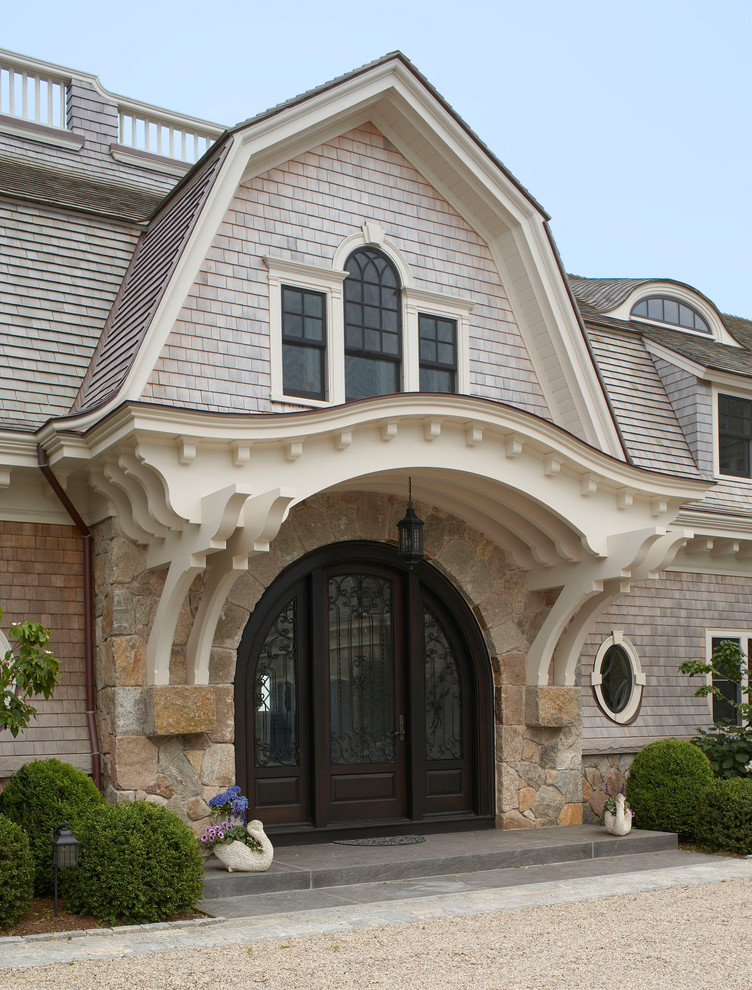 This is an example of an expansive traditional two-storey beige house exterior in Boston with wood siding, a gambrel roof and a shingle roof.