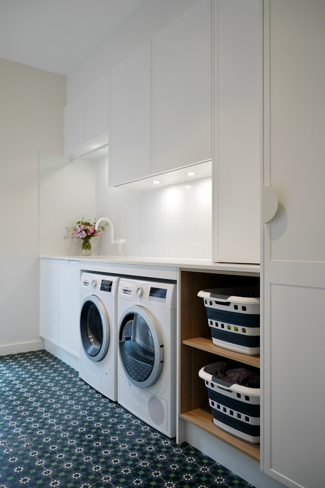 This is an example of a medium sized contemporary single-wall separated utility room in Sydney with a submerged sink, shaker cabinets, white cabinets, engineered stone countertops, white splashback, ceramic splashback, white walls, ceramic flooring, a side by side washer and dryer, green floors and white worktops.