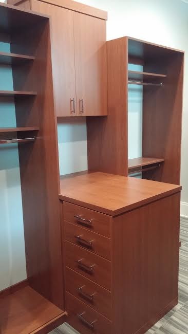 Design ideas for a mid-sized modern men's walk-in wardrobe in Tampa with flat-panel cabinets, brown cabinets, slate floors and grey floor.